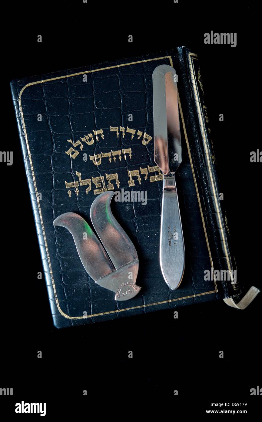 Instruments used in the Jewish religious circumcision ceremony brit milah, a knife and a foreskin guard, lie on a jewish prayer book in the rooms of the Israeli religious community in Hof, Germany, 26 July 2012. Photo: David Ebener Stock Photo