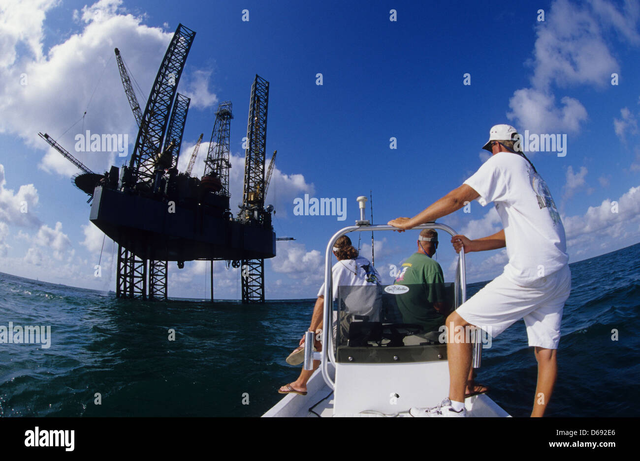 Men trolling and fishing near an oil rig drilling platform in the