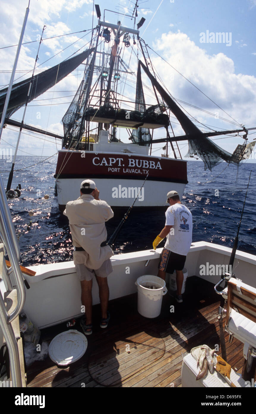 Fishermen buying chum from a shrimp boat in the Gulf of Mexico offshore from Port Aransas Texas Stock Photo