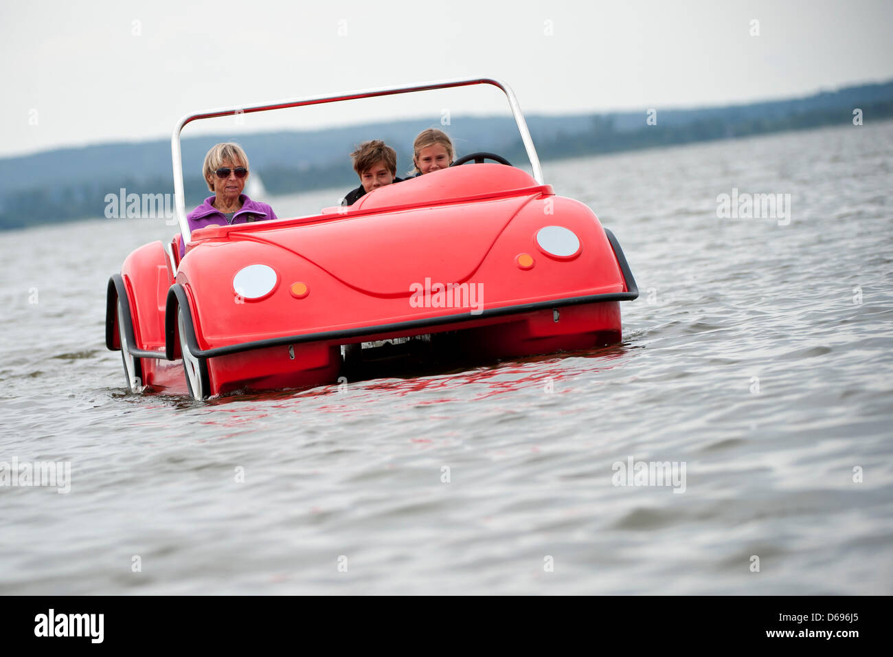 A family rides in a red paddle boat in the shape of a VW Beetle on Lake Steinhude in Steinhude, Germany, 31 July 2012. Even on cloudy days, the lake is a well-loved get-away location. Photo: Emily Wabitsch Stock Photo