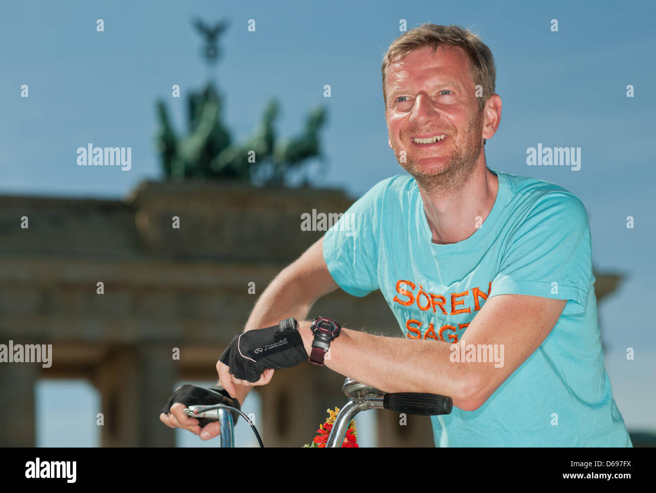 German comedian Michael Kessler poses with a folding bicycle from the 1970's in front of the Brandenburg Gate in Berlin, Germany, 01 August 2012. Kessler cycled with the folding bicycle 630 kilometers from Copenhagen to Berlin for the television show 'Kessler's Expeditions'. Photo: TIM BRAKEMEIER Stock Photo