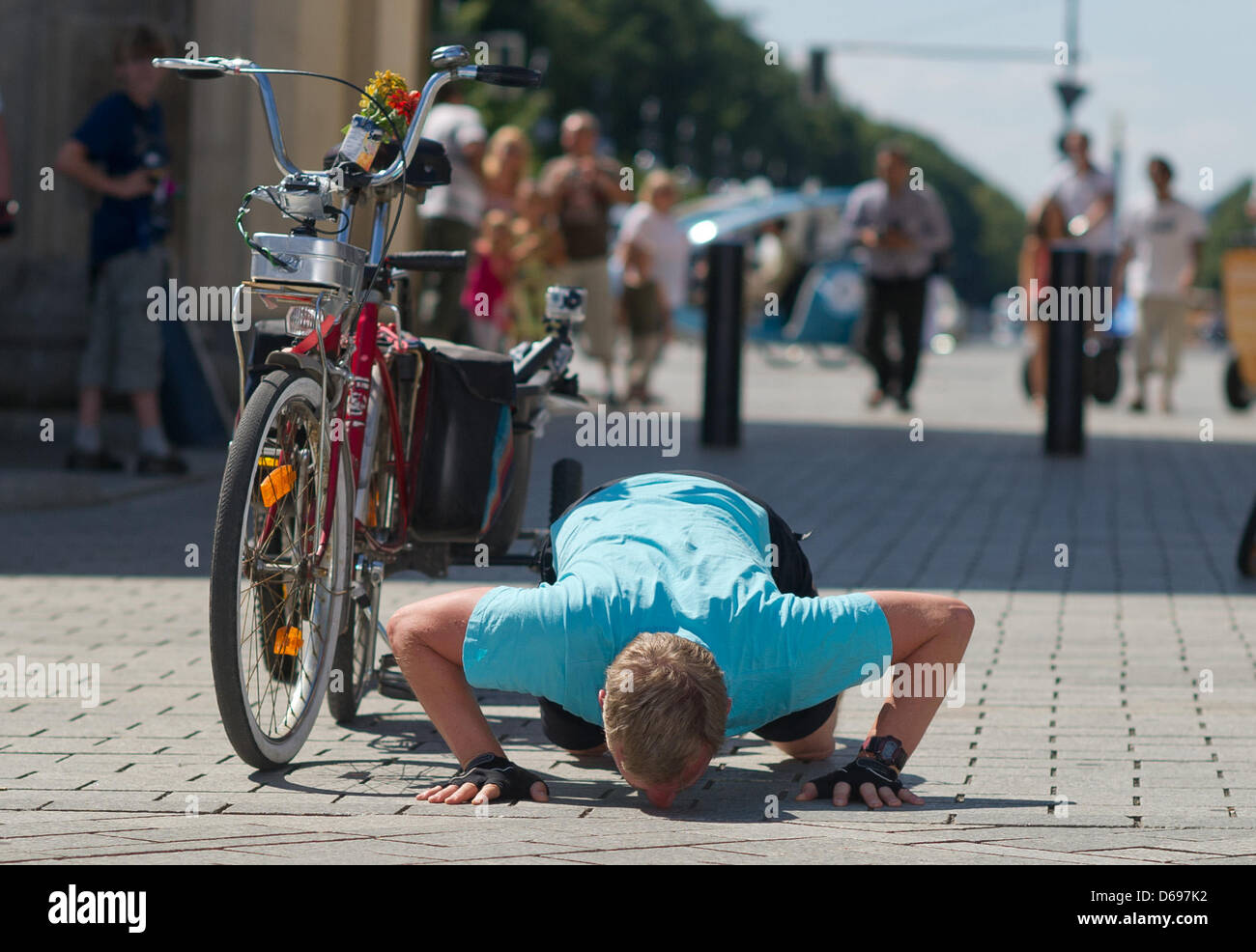 German comedian Michael Kessler kisses the ground next to a folding bicycle from the 1970's after his two week journey from Copenhagen in front of the Brandenburg Gate in Berlin, Germany, 01 August 2012. Kessler cycled with the folding bicycle 630 kilometers from Copenhagen to Berlin for the television show 'Kessler's Expeditions'. Photo: TIM BRAKEMEIER Stock Photo