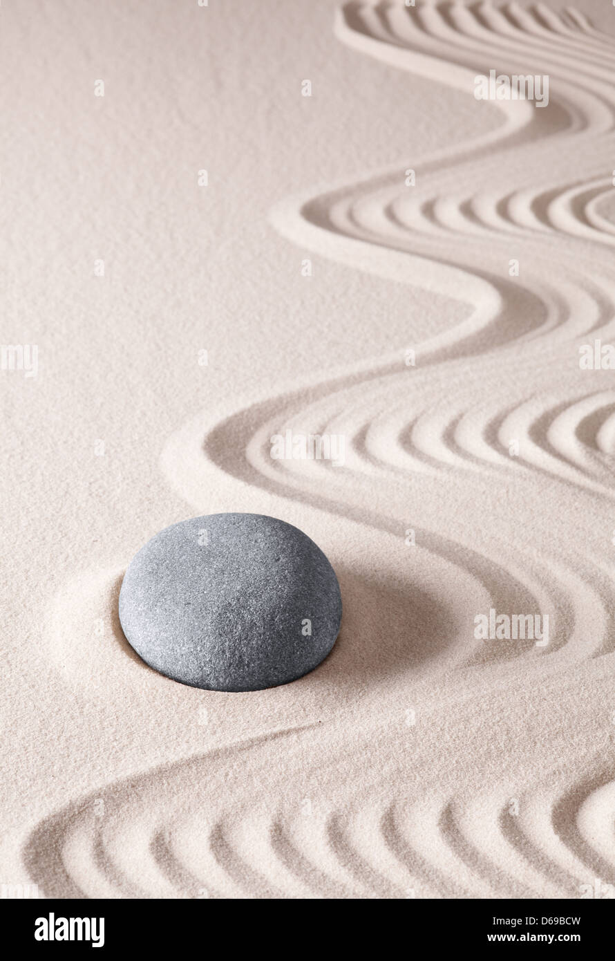Zen meditation stone concept for relaxation harmony and purity. A round rock in the sand. Stock Photo