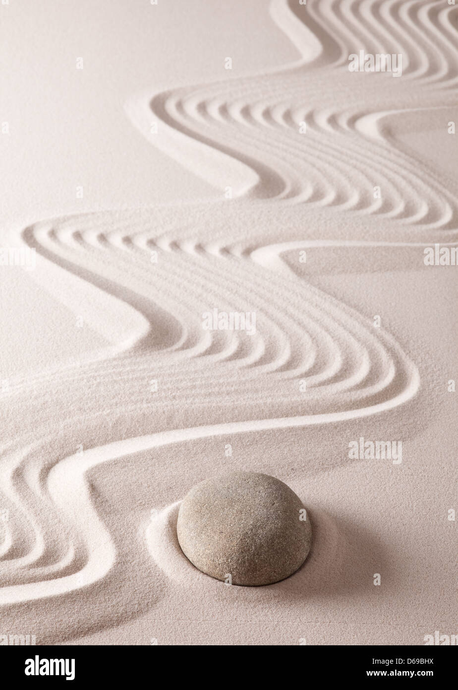 Zen stone garden with round rock and lines  raked in the sand, background image for meditation, yoga and spa wellness Stock Photo