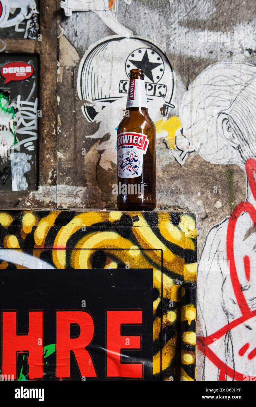 A beer bottle, graffiti and posters create a colourful stilllife in