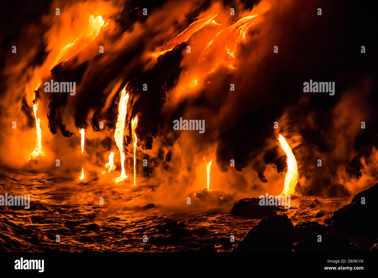 Lava flowing over cliff into water Stock Photo