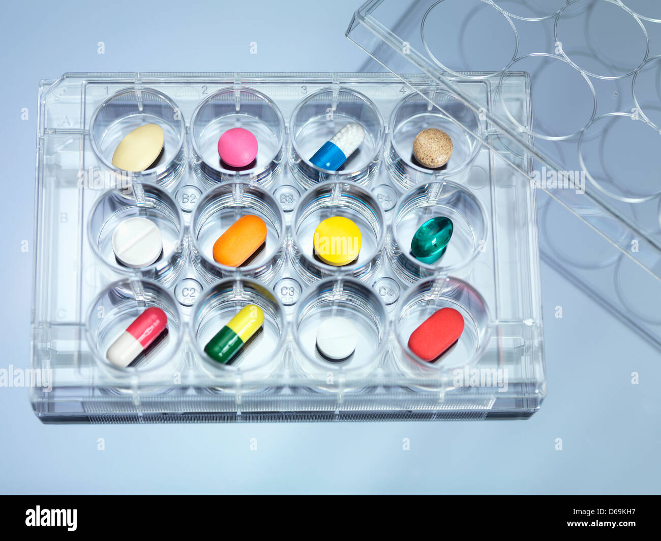 A variety of drugs sitting in a multi well sample tray Illustrating drug clinical trial Stock Photo