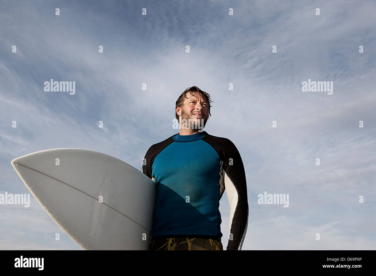 Surfer carrying board outdoors Stock Photo