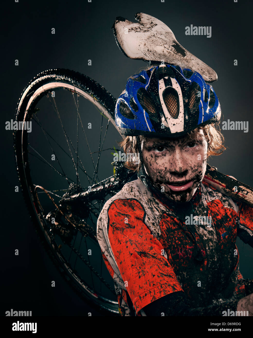 Mud splattered cyclist carrying bicycle Stock Photo