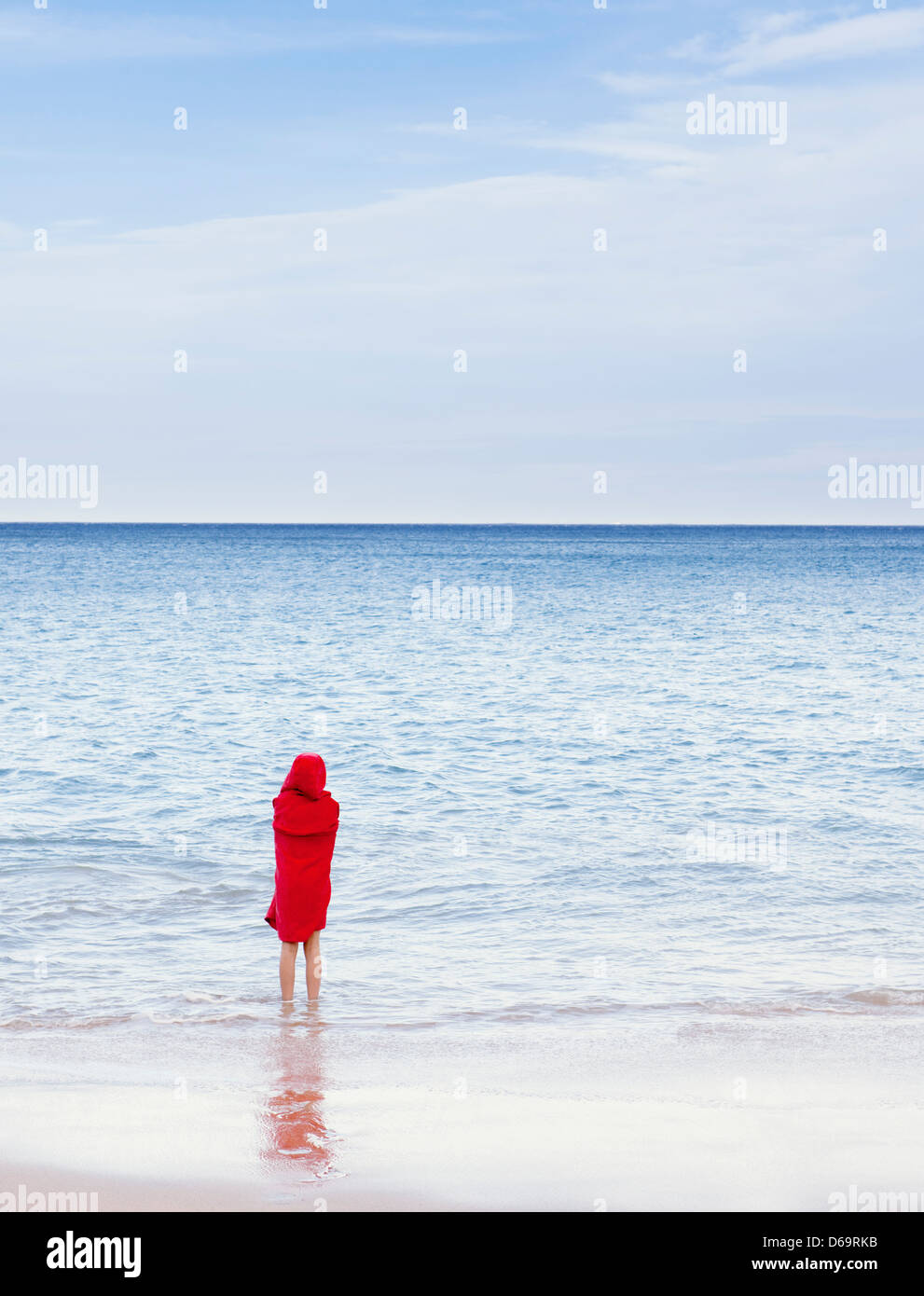Girl standing in waves on beach Stock Photo