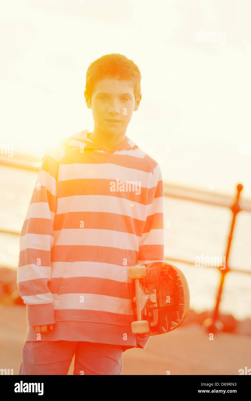 Boy holding skateboard outdoors Stock Photo