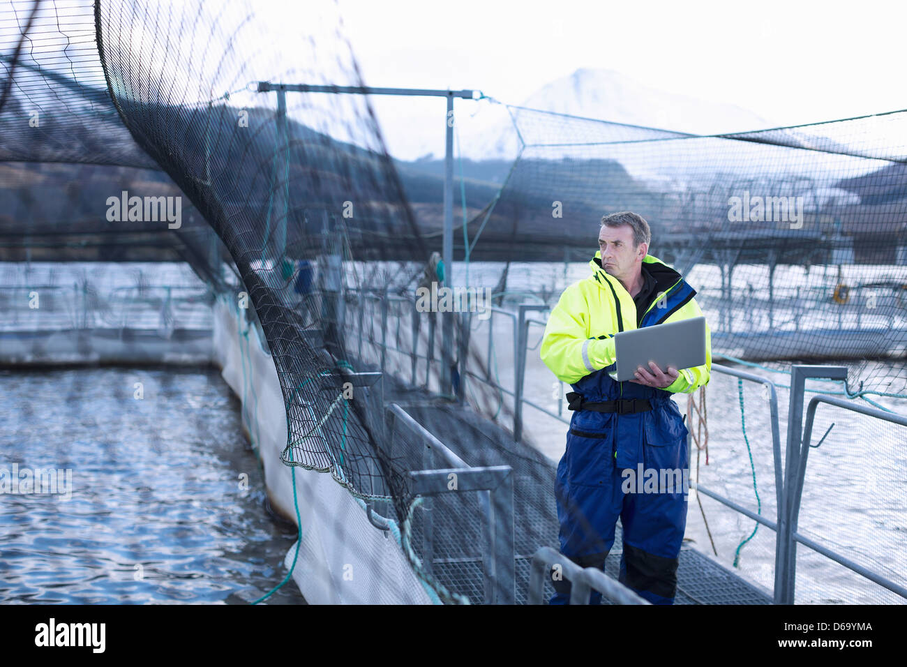 Worker using laptop at salmon farm Stock Photo