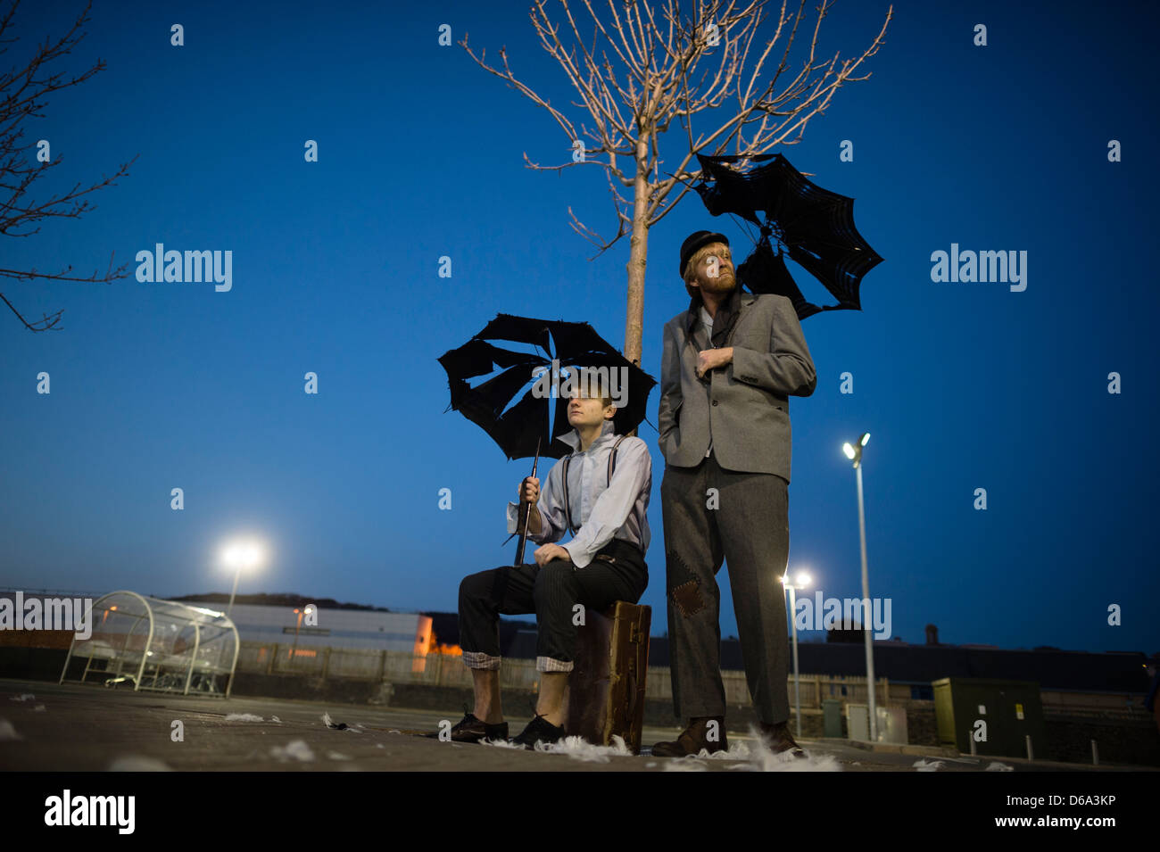 2 actors performing as Vladimir & Estragon in Samuel Beckett's classic play 'Waiting for Godot' in a deserted carpark at night Stock Photo