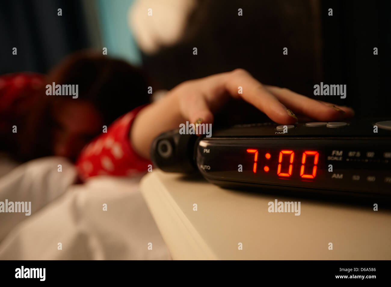 alarm clock early morning with early twenties woman turning off alarm