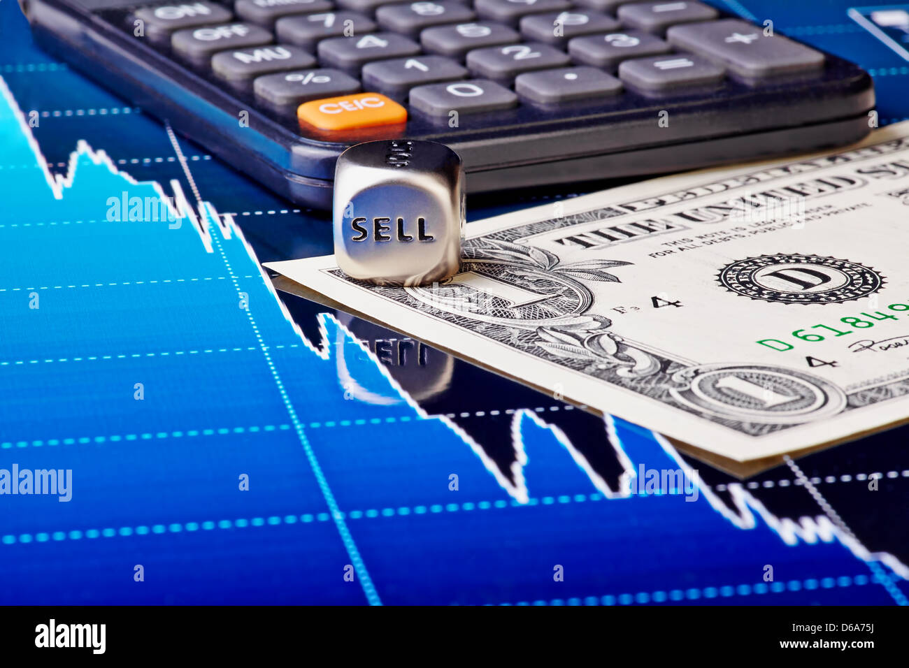 Close-up dices cube with the word SELL, one-dollar banknote, calculator and downtrend financial chart as background. Stock Photo