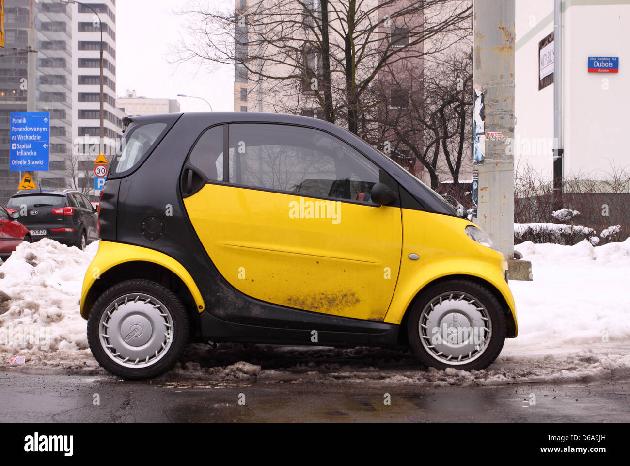 Yellow Smart Car parked in snow in Warsaw city centre Poland Stock Photo