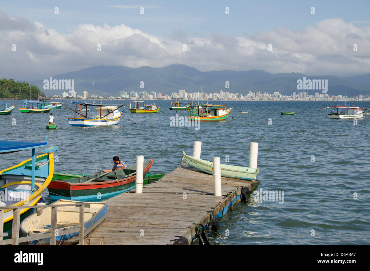 Brazil, state of Santa Catarina, Porto Belo. Colorful local fishing boats with city skyline in distance. Stock Photo