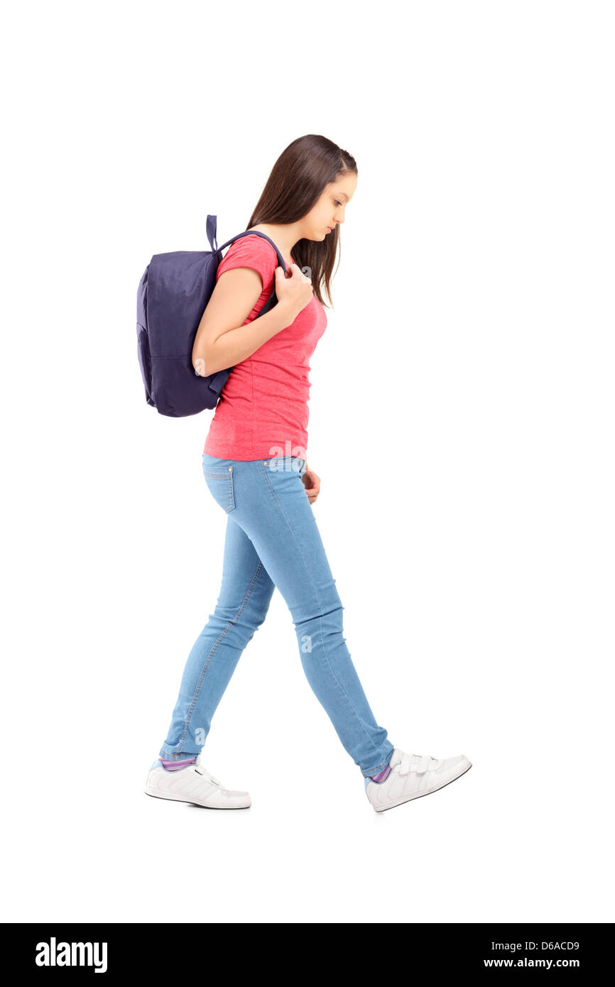 Full length portrait of a sad female student walking with a backpack, isolated on white background Stock Photo