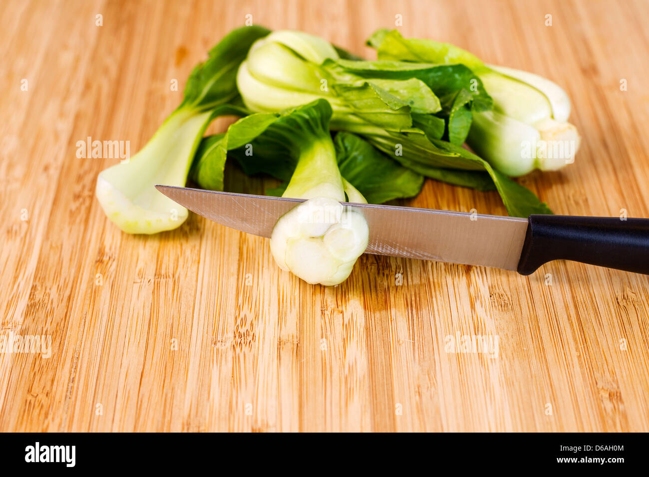 Closeup horizontal photo of washed Chinese Choy vegetable with cutting knife on natural bamboo wood Stock Photo