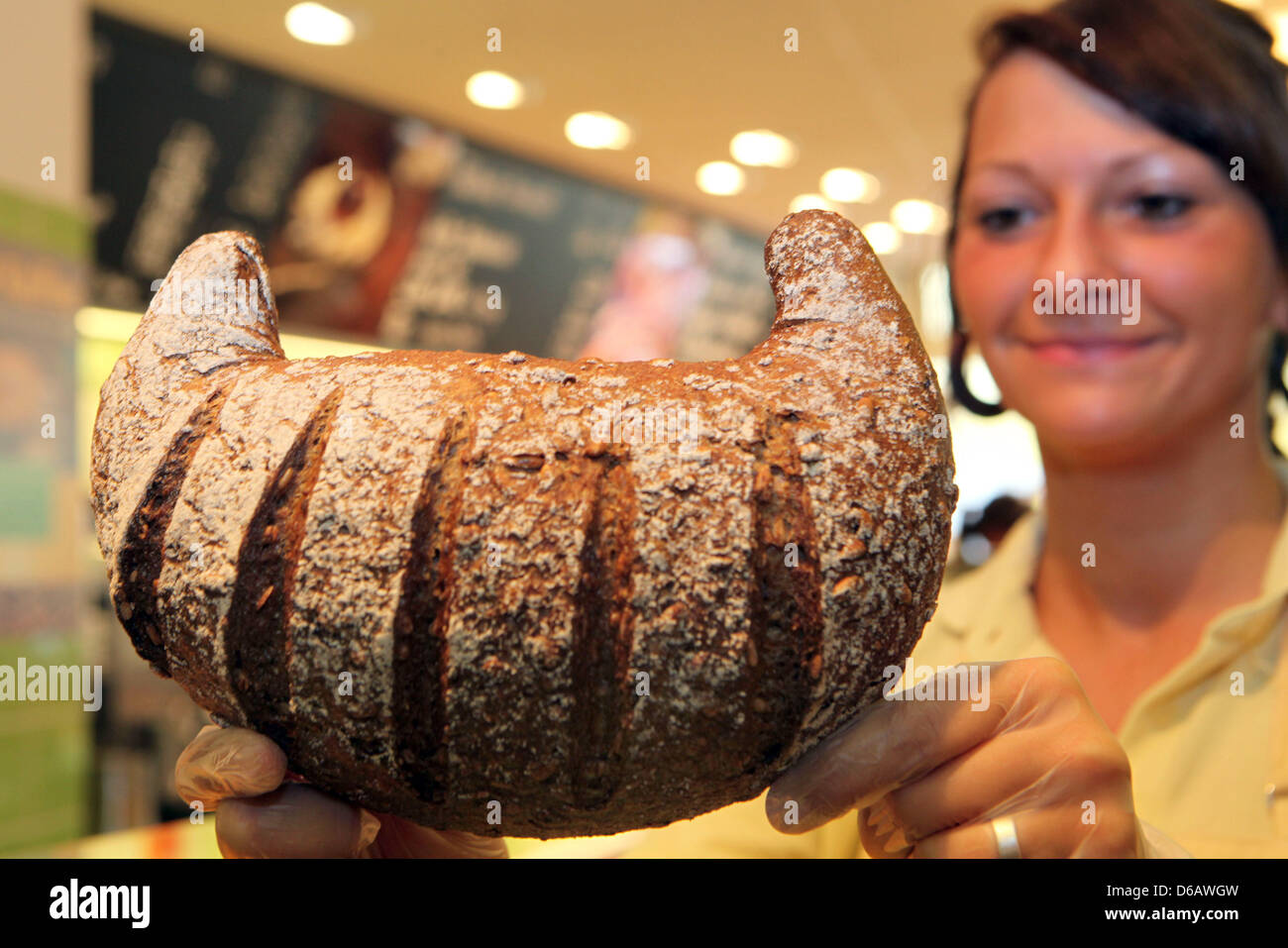A saleswoman presents a fresh organic canoe bread at a Fahland Bakery