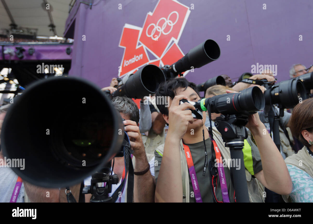 Photographer Dan Chung (C) of the British Newspaper 'The Guardian' is shooting the Athletics at the Olympic Games in London with his Smartphone. Chung said, he wanted to do something different and show, that is possible to make proper pictures with a simple Smartphone. The only help is a attached binocular to his phone. Photo: Michael Kappeler dpa  +++(c) dpa - Bildfunk+++ Stock Photo