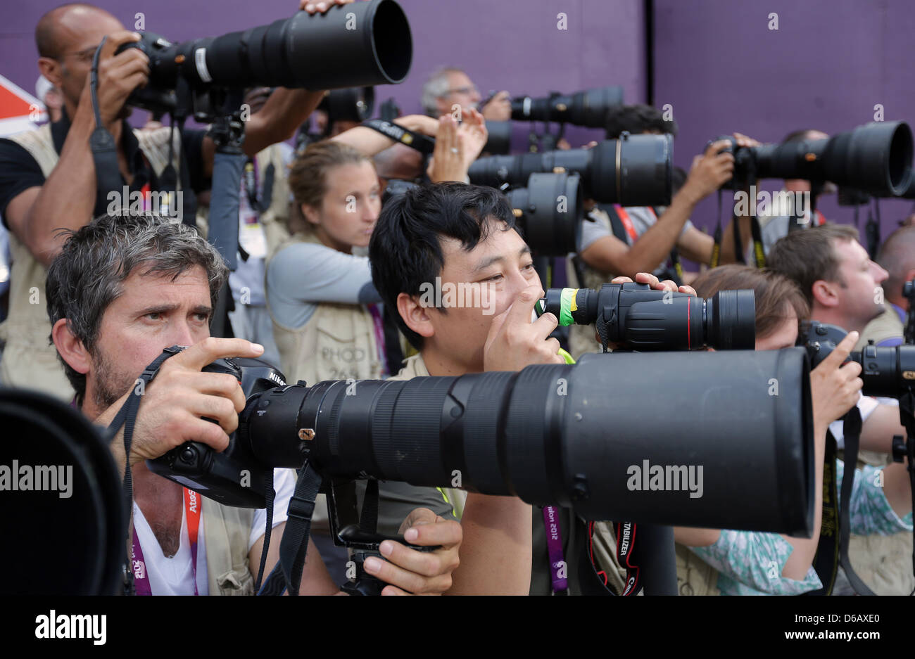Photographer Dan Chung (C) of the British Newspaper 'The Guardian' is shooting the Athletics at the Olympic Games in London with his Smartphone. Chung said, he wanted to do something different and show, that is possible to make proper pictures with a simple Smartphone. The only help is a attached binocular to his phone. Photo: Michael Kappeler dpa Stock Photo