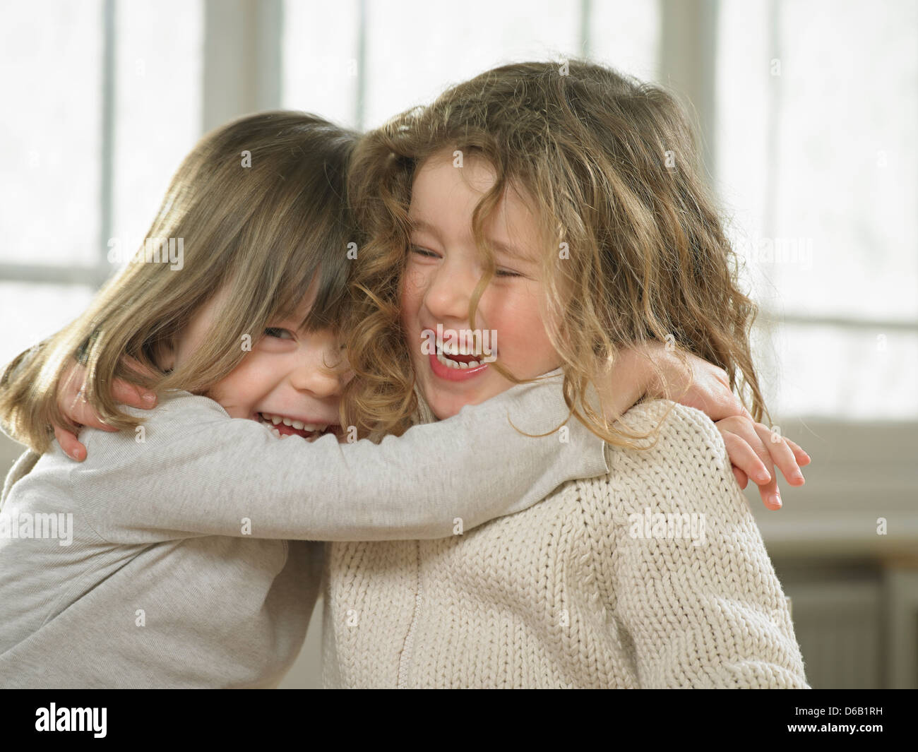 Smiling girls hugging indoors Stock Photo