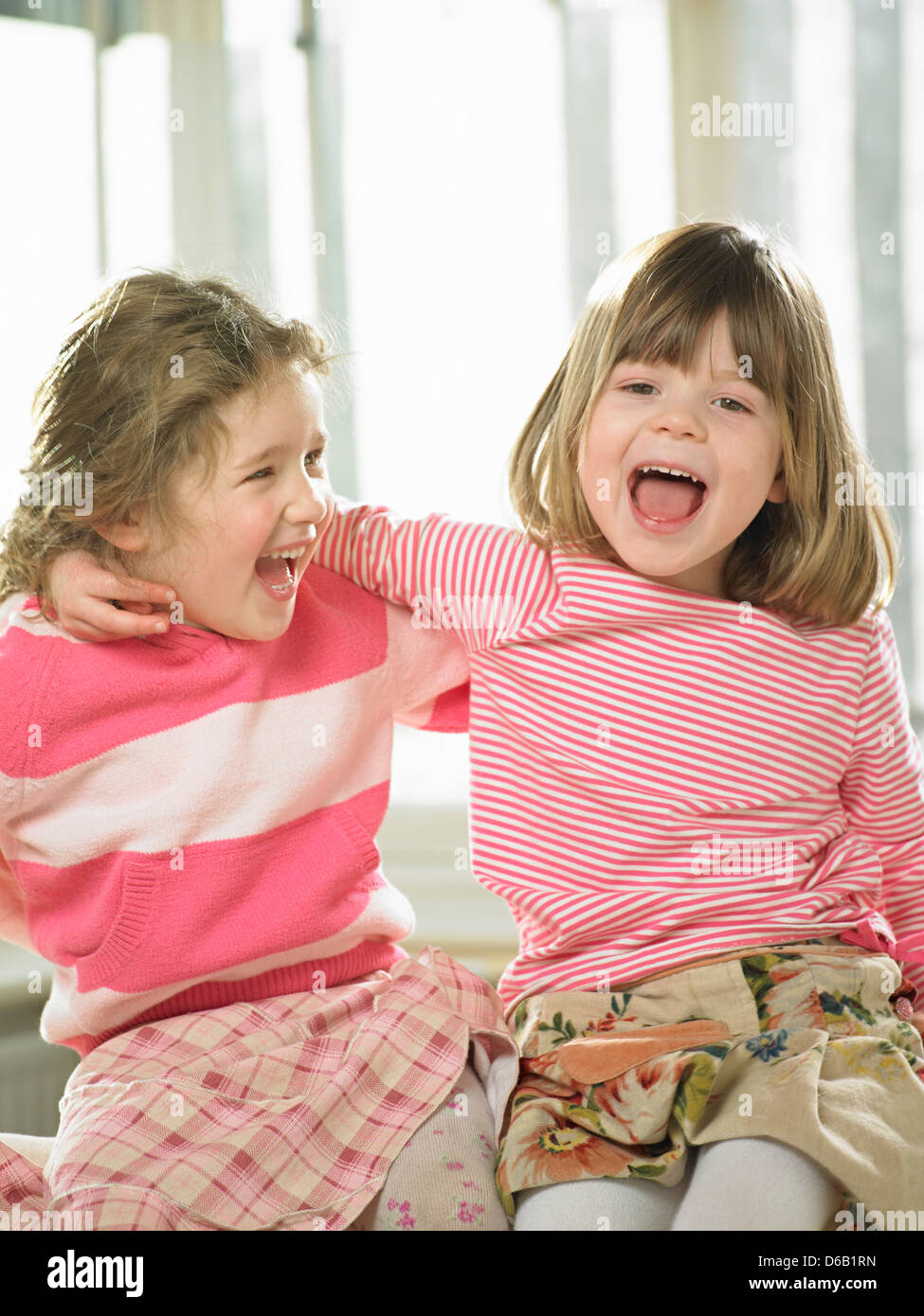 Girls smiling together indoors Stock Photo