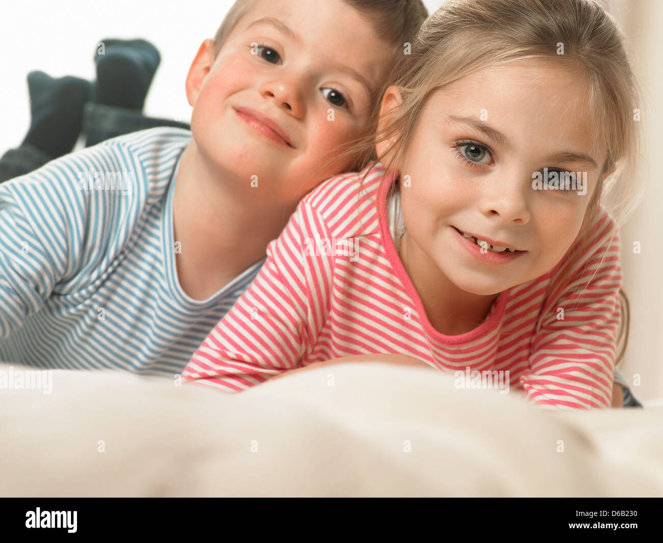 Children laughing together on bed Stock Photo