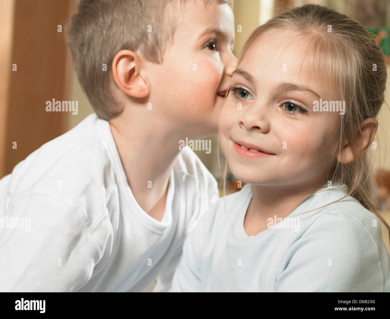 Boy whispering in girls ear Stock Photo