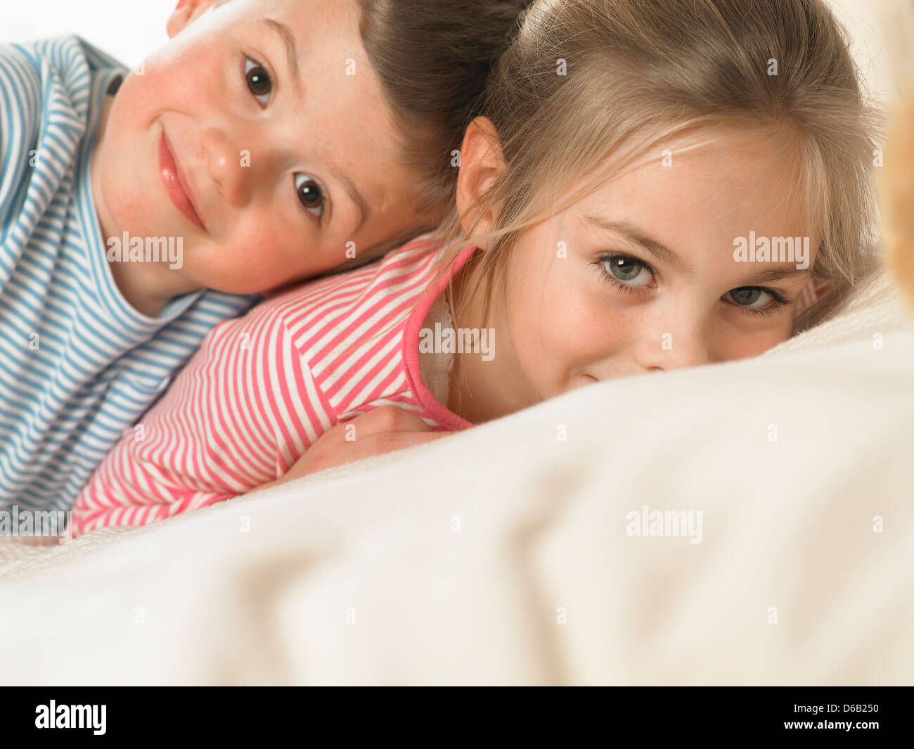 Children smiling together on bed Stock Photo