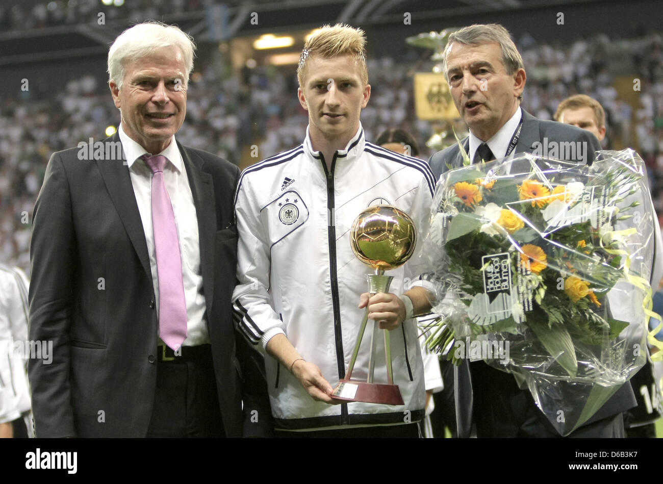 Germany's Marco Reus (M) is awarded the 'Player of the Season 2011/12' by  Kicker sports magazine chief editor Rainer Holzschuh (L) and DFB President  Wolfgang Niersbach before the friendly soccer match between