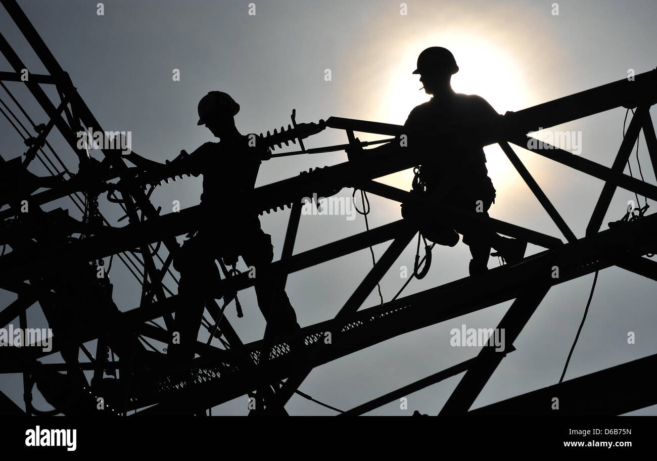 Two workers attach insulators near Erfurt, Germany, 21 August 2012. Currently, the high tension power lines are being built between Vieselbach and Arnstadt for Energienetze GmbH in Thuringia at a cost of 1.7 million euros. Photo: Martin Schutt Stock Photo