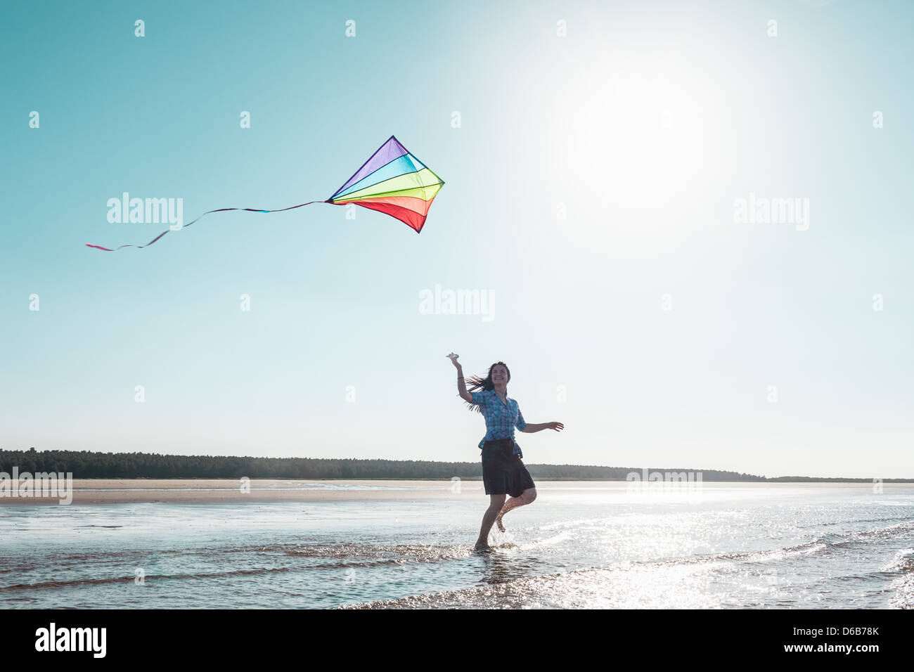 Woman flying kite on beach Stock Photo