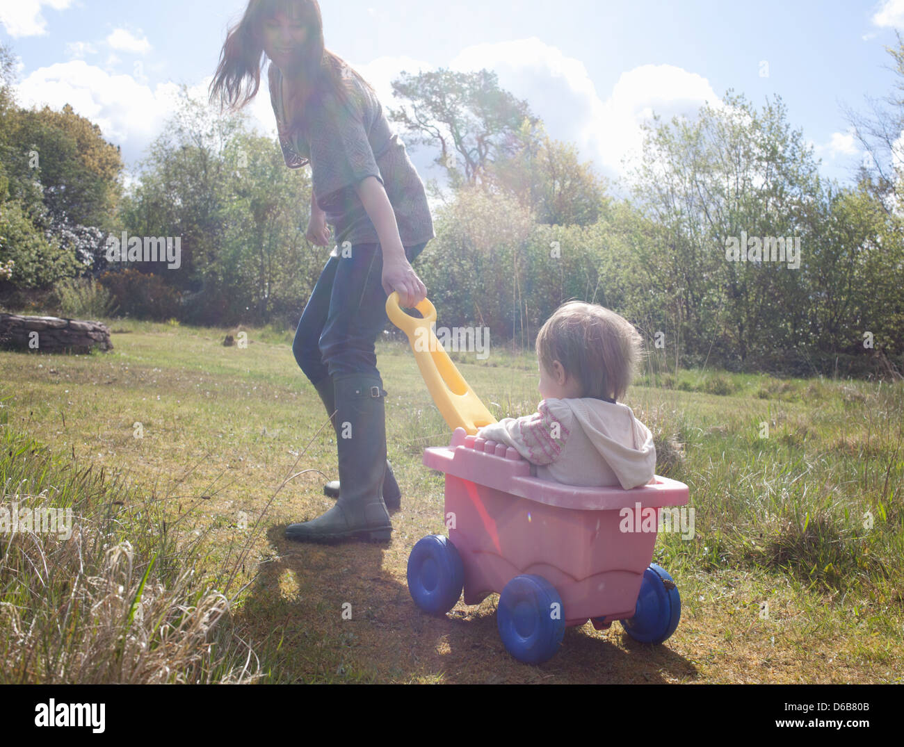 Mother pulling toddler girl in wagon Stock Photo