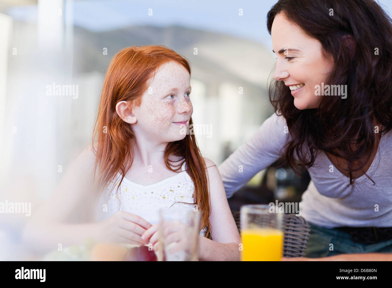 Mother smiling at daughter at breakfast Stock Photo
