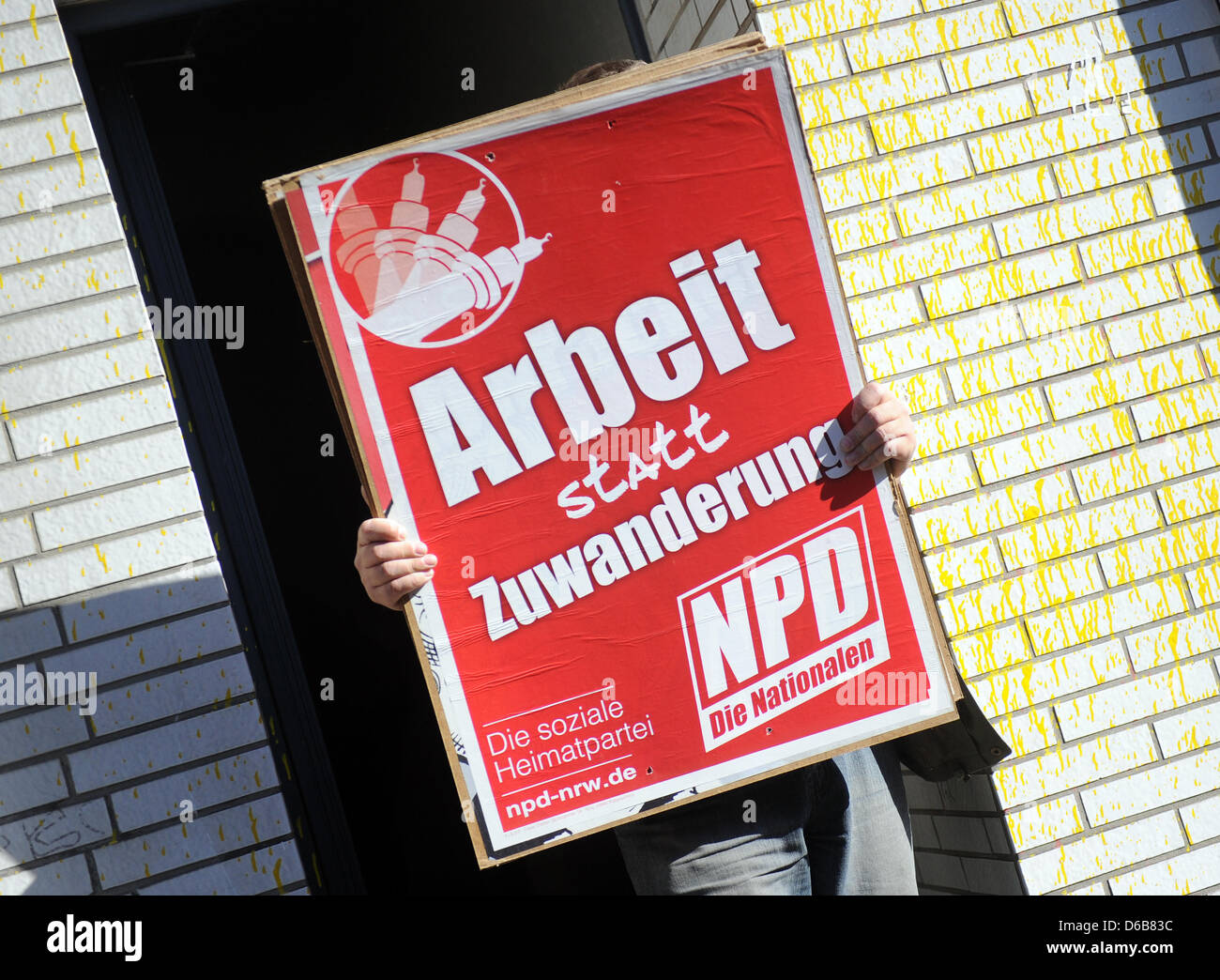 A man carries NPD (a German far-right party) posters out of a house after it was searched in Dortmund, Germany, 23 August 2012. Police were out in force after the North Rhine-Westphalian Interior Minister outlawed three right-wing extremist organizations, the 'Kameradschaft Aachener Land', the 'Nationaler Widerstand Dortmund' and the 'Kameradschaft Hamm'. Photo: CAROLINE SEIDEL Stock Photo