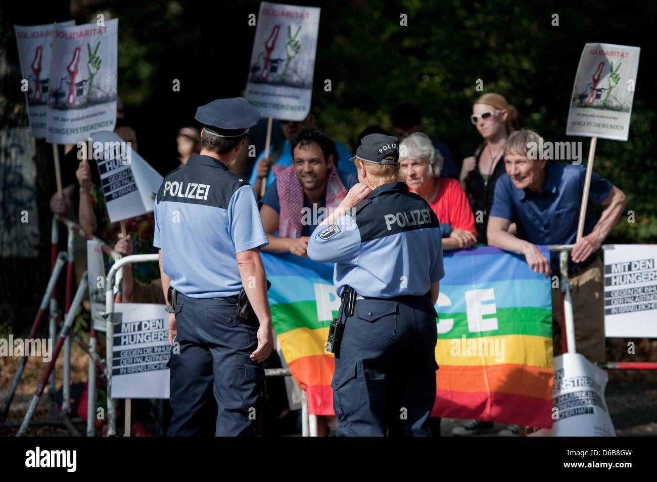 Two police officers watch a group of protesters with banners in front of the Israeli embassy in Berlin, Germany, 23 August 2012. The demonstration organised by 'Addameer' is aimed against alleged abuses of Palestinian prisoners in Israeli prisoners. Photo: ROBERT SCHLESINGER Stock Photo