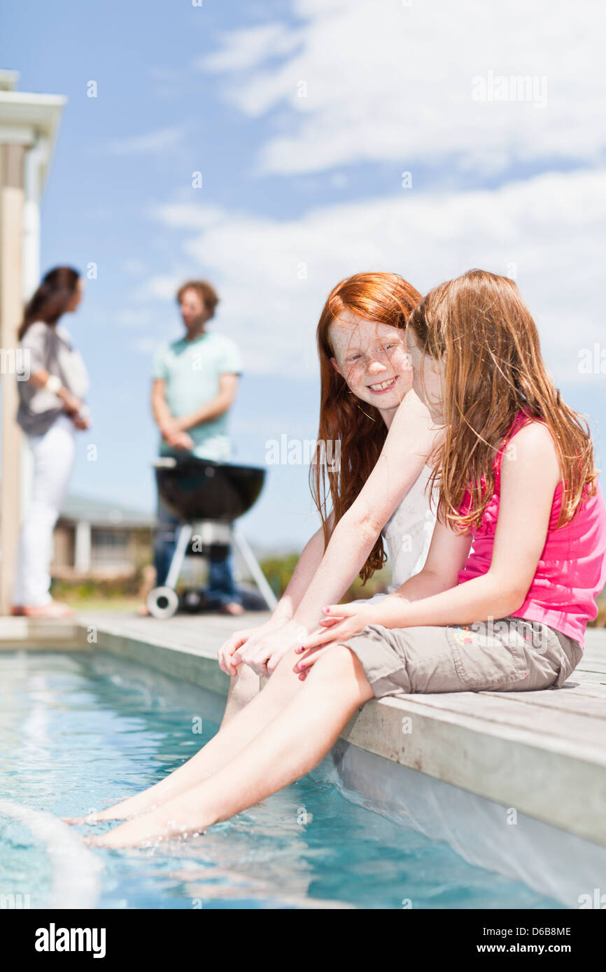 Girls dangling feet in swimming pool Stock Photo