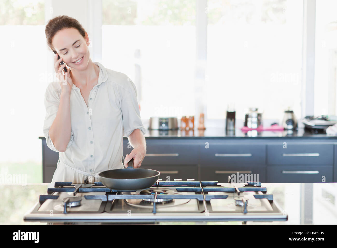 Woman on cell phone cooking Stock Photo