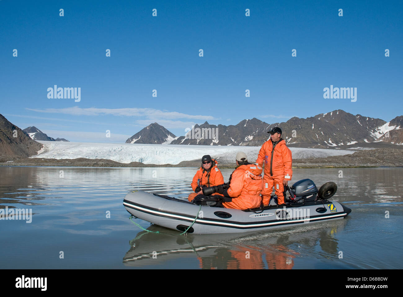 Norway Svalbard Archipelago Spitsbergen Photographers in a zodiac check out a beautiful rugged retreating glacier in summer. Stock Photo