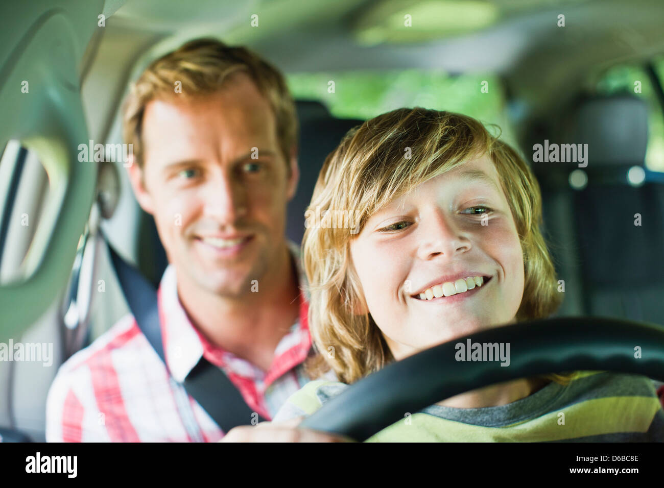 Boy driving car on fathers lap Stock Photo