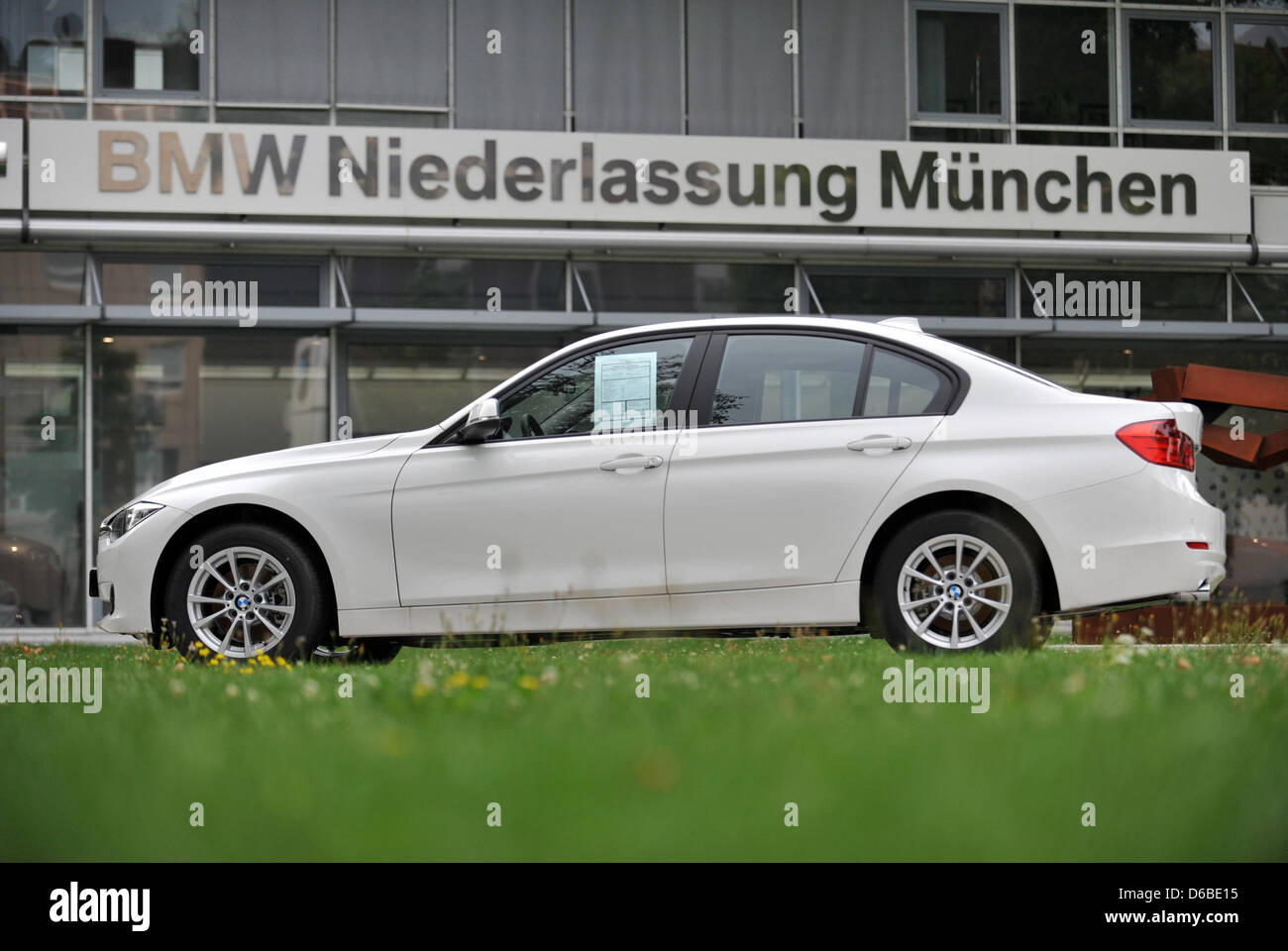 A BMW sits in front of a BMW dealership on the Frankfurter Ring in