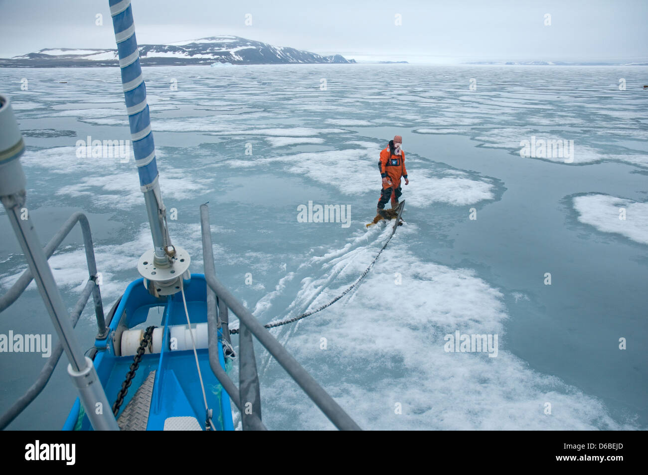 Norway, Svalbard Archipelago, Spitsbergen. Sailboat captain drops anchor in fjord ice along the coast. Stock Photo