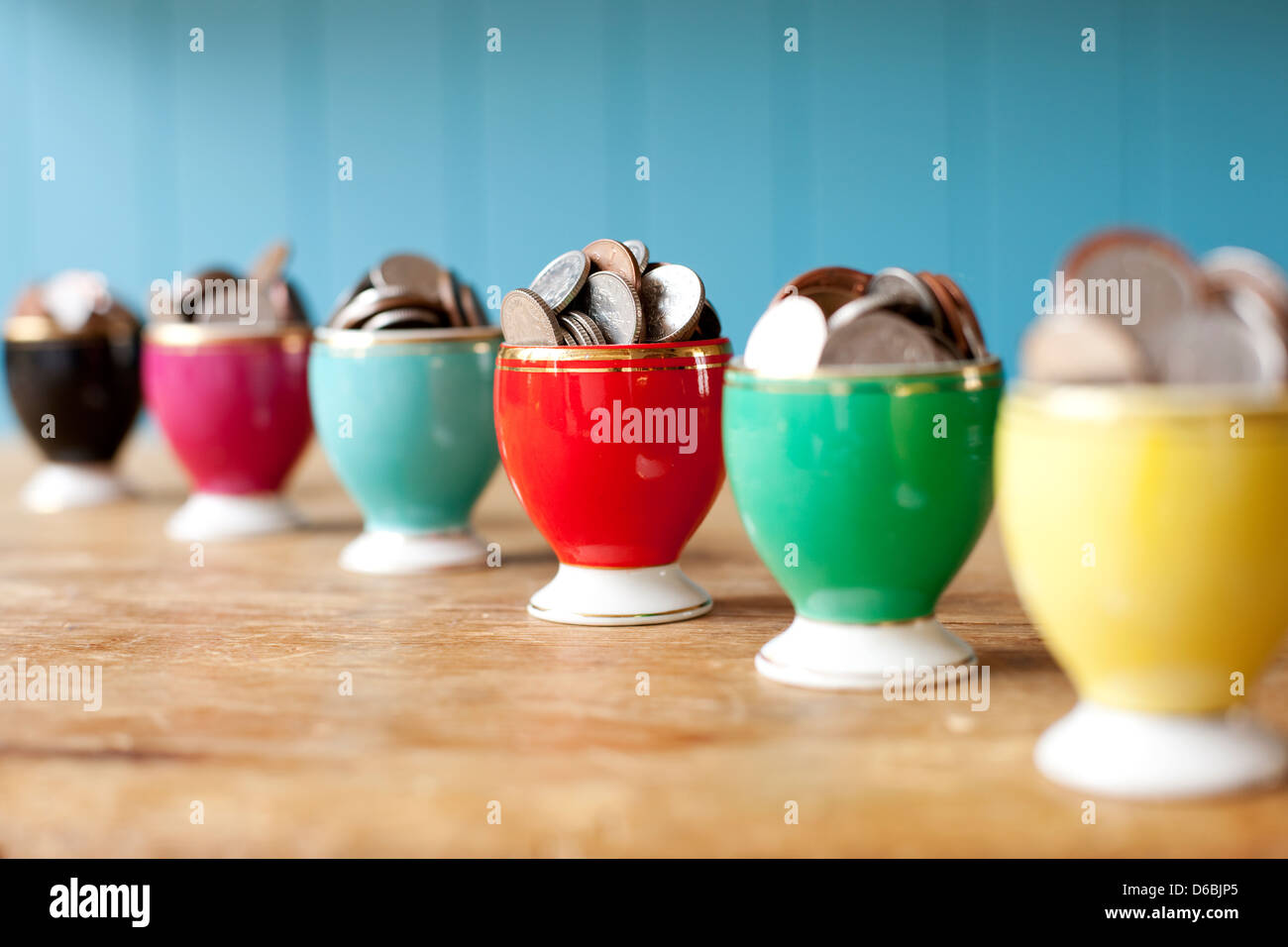 Egg cups full of money on desk Stock Photo