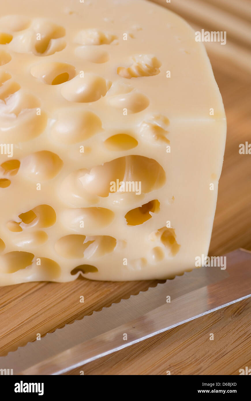 yellow cheese with large holes on plank Stock Photo