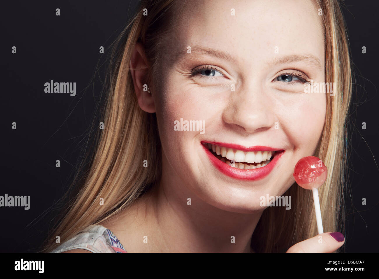 Smiling woman eating lollipop Stock Photo