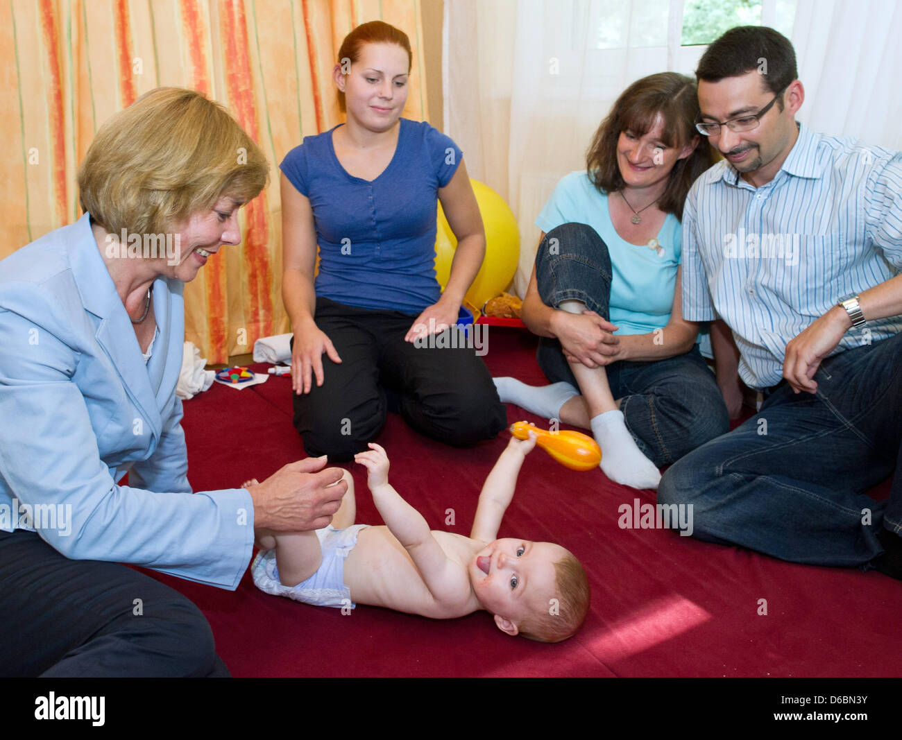 Partner of the German President, Daniela Schadt (L), plays with nine-month-old Lara Hohmann while the parents Sieglinde Hohmann and Marco Heinemann as weel as physiotherapist Svenja Dudek (2-L) are watching them at the after-care hospital for children Berlin-Brandenburg in Bernau, Germany, 03 September 2012. The little girl suffered from a hole in the cardiac septum and now is reco Stock Photo
