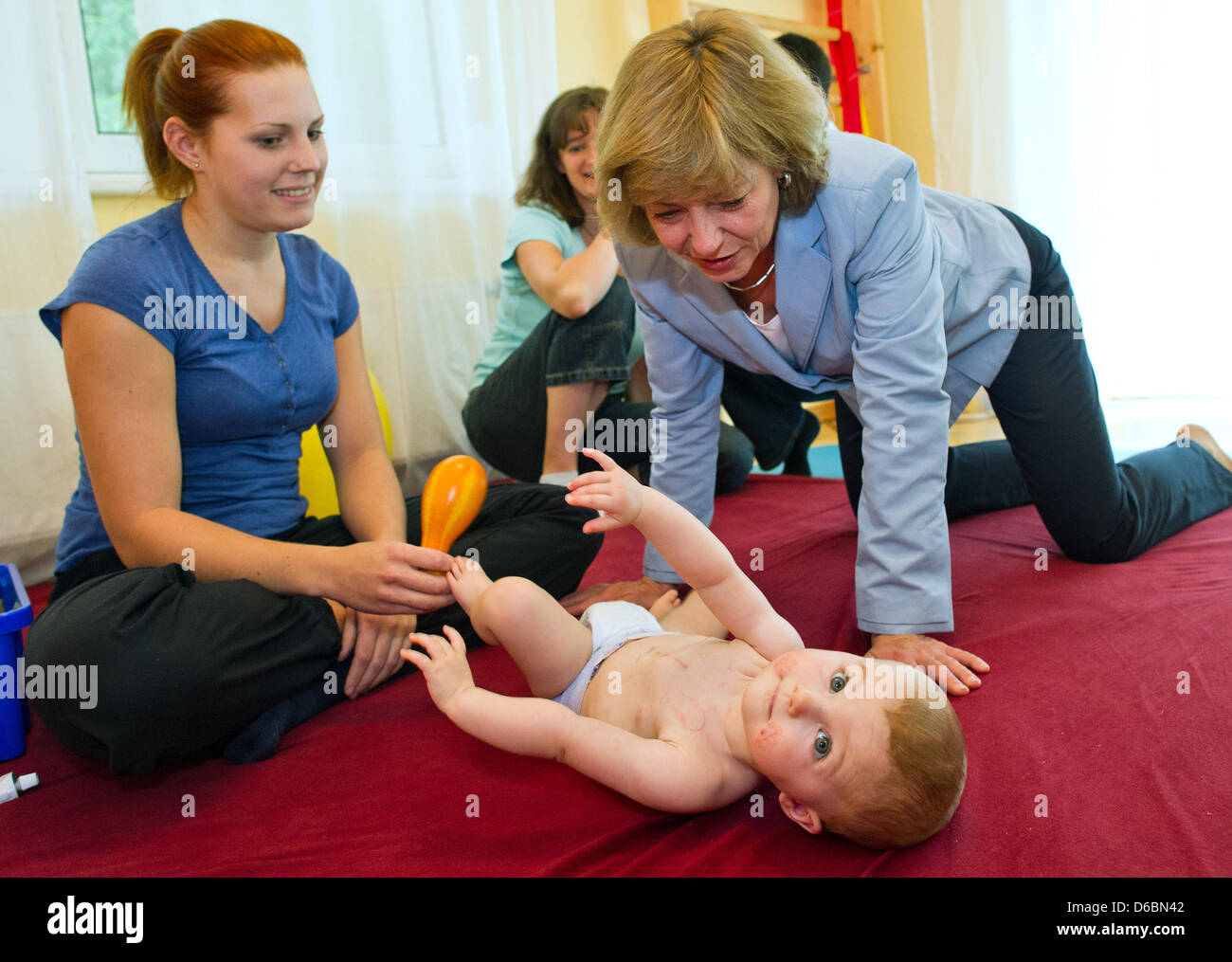 Partner of the German President, Daniela Schadt (front), plays with nine-month-old Lara Hohmann while physiotherapist Svenja Dudek (L) and mother Sieglinde Hohmann are watching them at the after-care hospital for children Berlin-Brandenburg in Bernau, Germany, 03 September 2012. The little girl suffered from a hole in the cardiac septum and now is recovering from the surgery. Danie Stock Photo