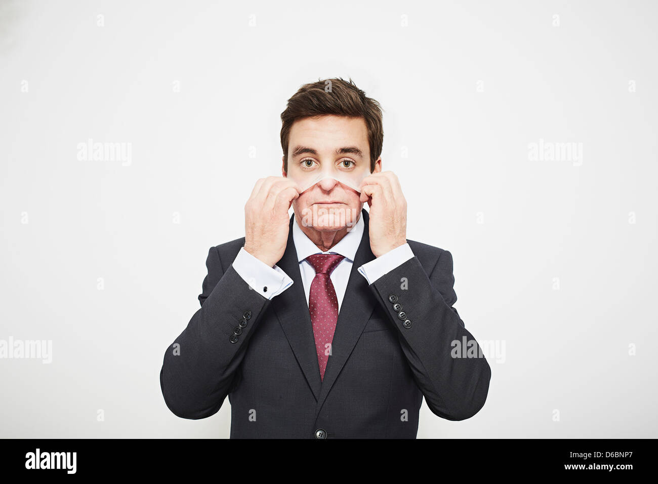 Businessman pulling on mask Stock Photo Alamy
